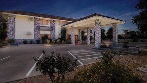 A two-story building with a covered entrance and a landscaped driveway.