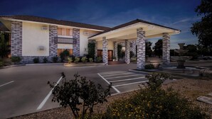 A two-story building with a covered entrance and a landscaped driveway. - Red Roof Inn Ridgecrest (Ridgecrest)