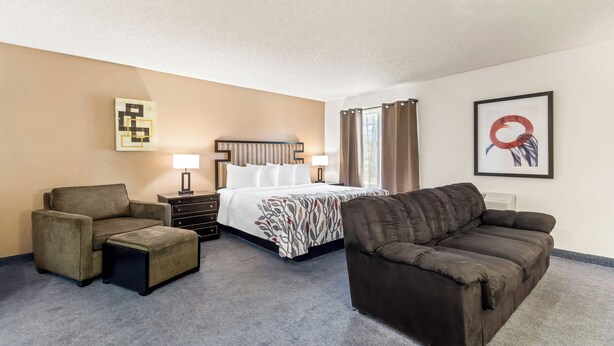 A hotel room with a bed, two armchairs, a sofa, a small table, and a lamp. - Red Roof Inn Ridgecrest (Ridgecrest)