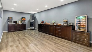 A spacious room with a wooden floor, a kitchenette area with a refrigerator, microwave, and coffee maker, and a small refrigerator with beverages. - Red Roof Inn Ridgecrest (Ridgecrest)