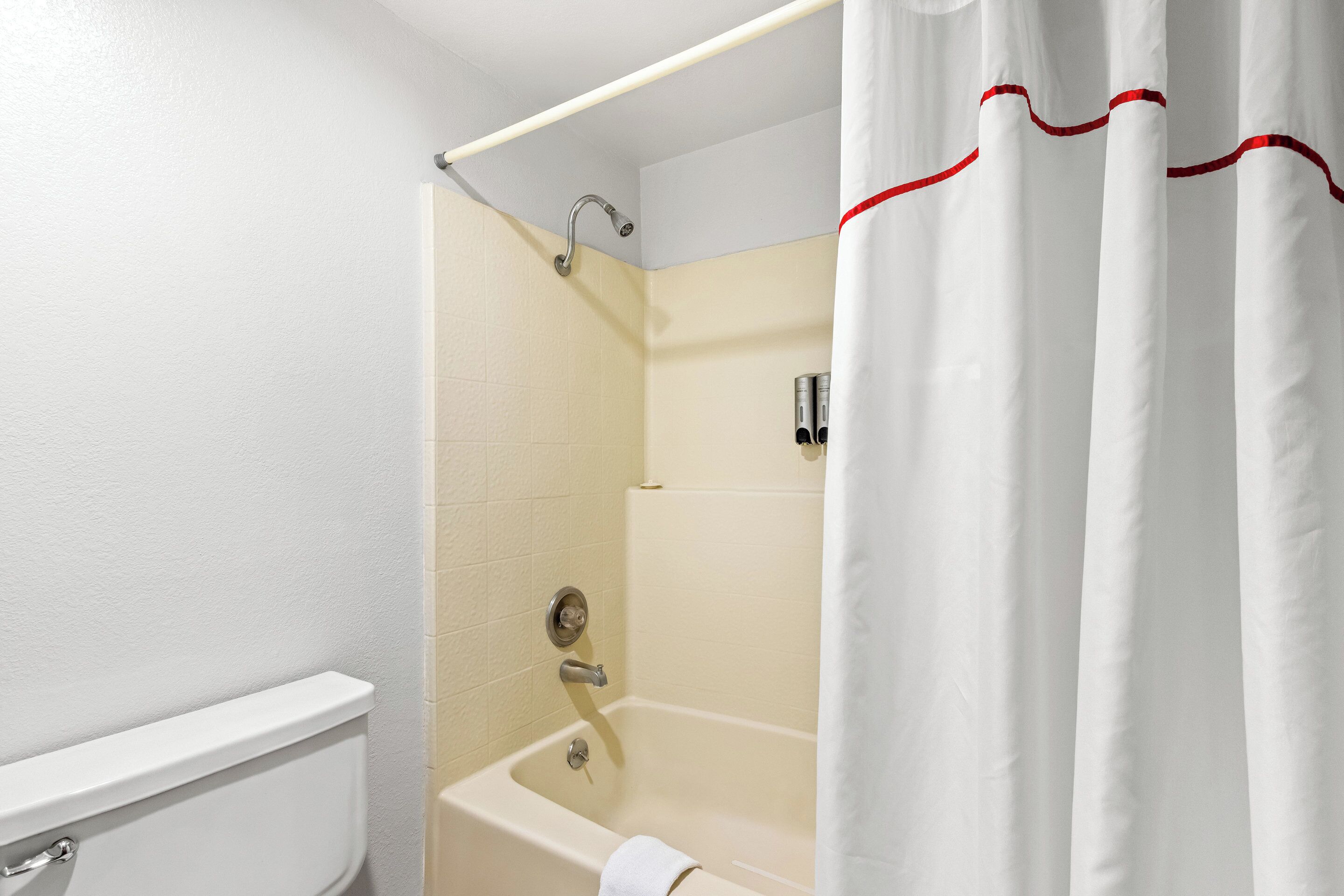 Un baño con bañera, inodoro y cortina de ducha.