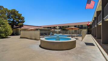 A courtyard with a central fountain, outdoor seating, and a pool area.