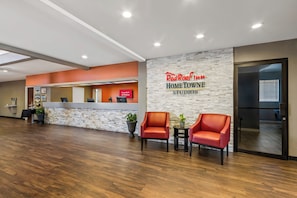A reception area with a stone wall, a reception desk, and two red chairs.