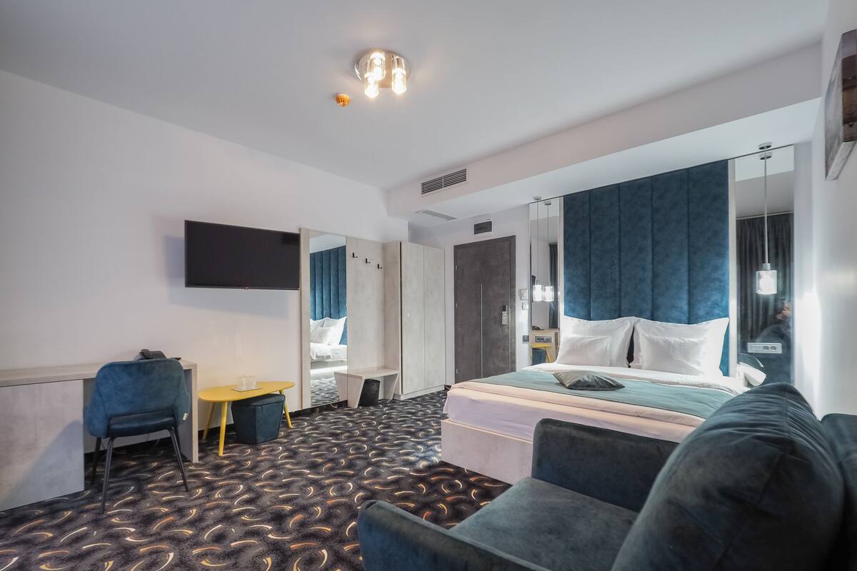 Une chambre d’hôtel équipée d’un lit, d’un bureau, d’une chaise, d’un canapé, d’une télévision et d’un miroir.