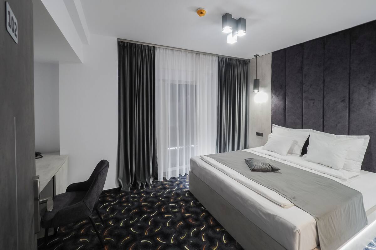 Une chambre d’hôtel moderne, dotée d’un grand lit, d’un bureau et d’une chaise.