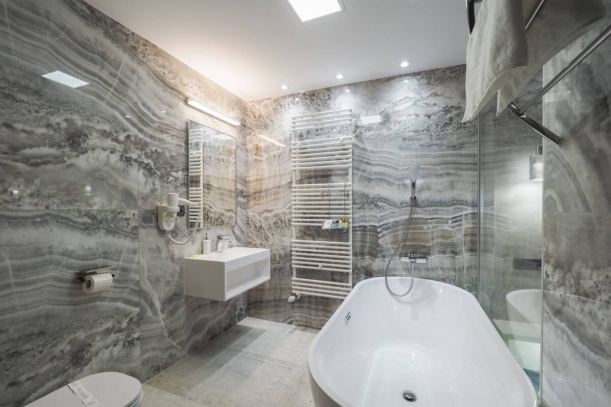 Une salle de bain moderne avec une baignoire sur pieds, un meuble-lavabo avec miroir et une douche à l’italienne.