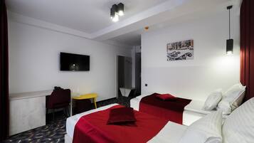 Een hotelkamer met twee bedden, een televisie, een kleine tafel en een schilderij aan de muur.