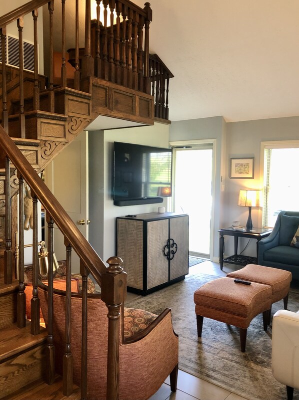 Una escalera que lleva al segundo piso, una sala de estar con televisor, sofá y mesa de centro.