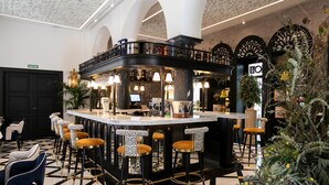 A bar area with a checkered floor, bar stools, and a counter with a television. - Hotel Casa Palacio Don Ramón 5* GL by Kaizen Hoteles (Seville)