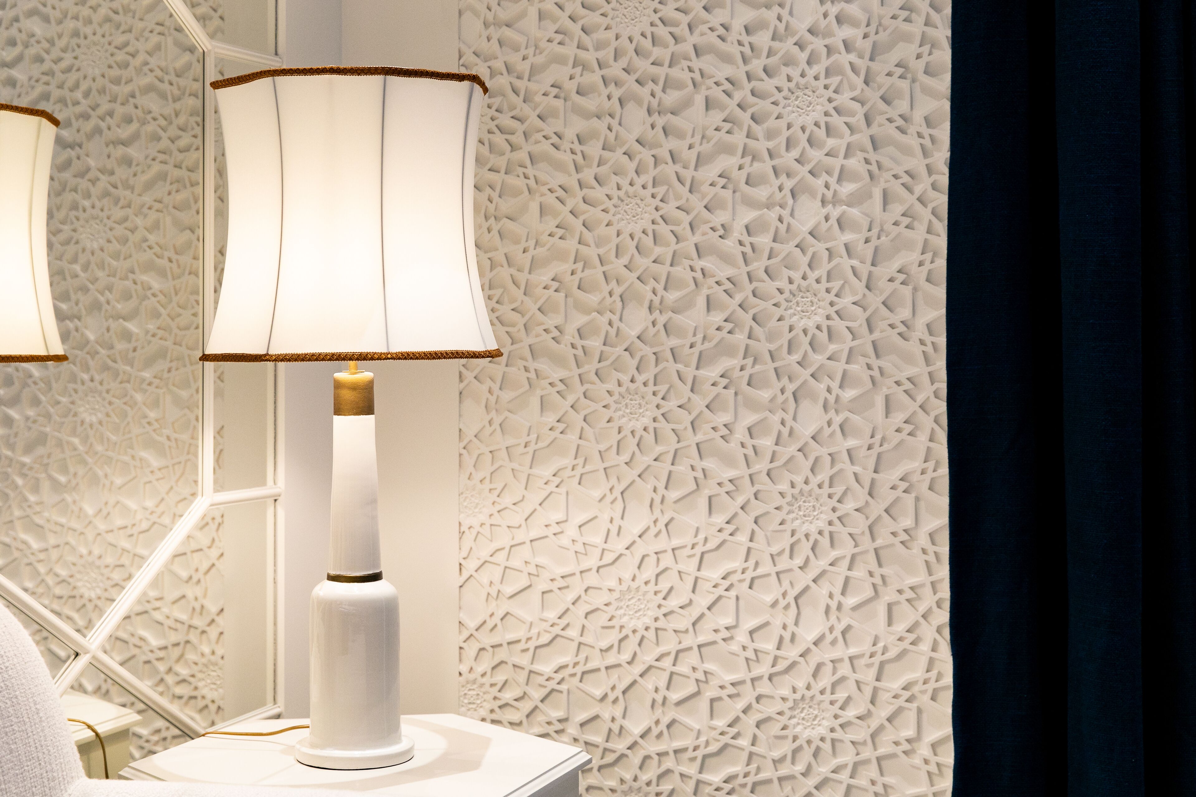 A modern room with a textured wall and a white lamp on a bedside table.