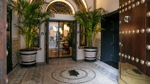 A grand entrance with a decorative archway, two potted plants, and a patterned floor. - Hotel Casa Palacio Don Ramón 5* GL by Kaizen Hoteles (Seville)