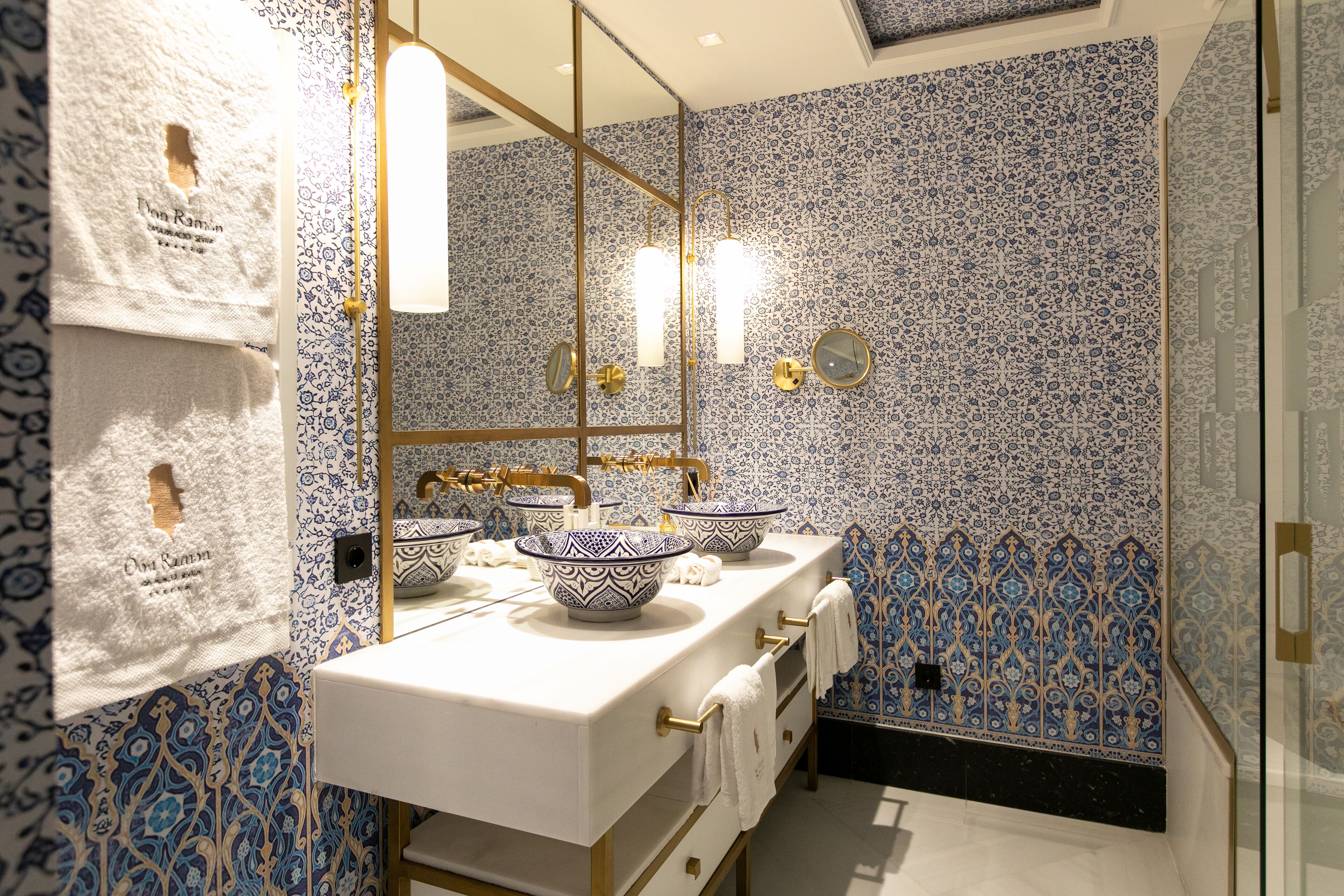 A bathroom with a white sink, two bowls, a mirror, and patterned walls.