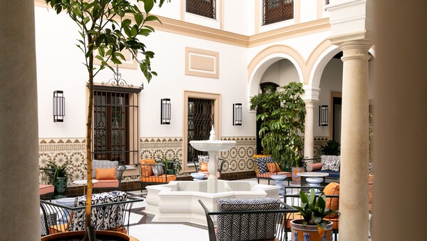 A courtyard with a fountain, seating areas, and potted plants. - Hotel Casa Palacio Don Ramón 5* GL by Kaizen Hoteles (Seville)