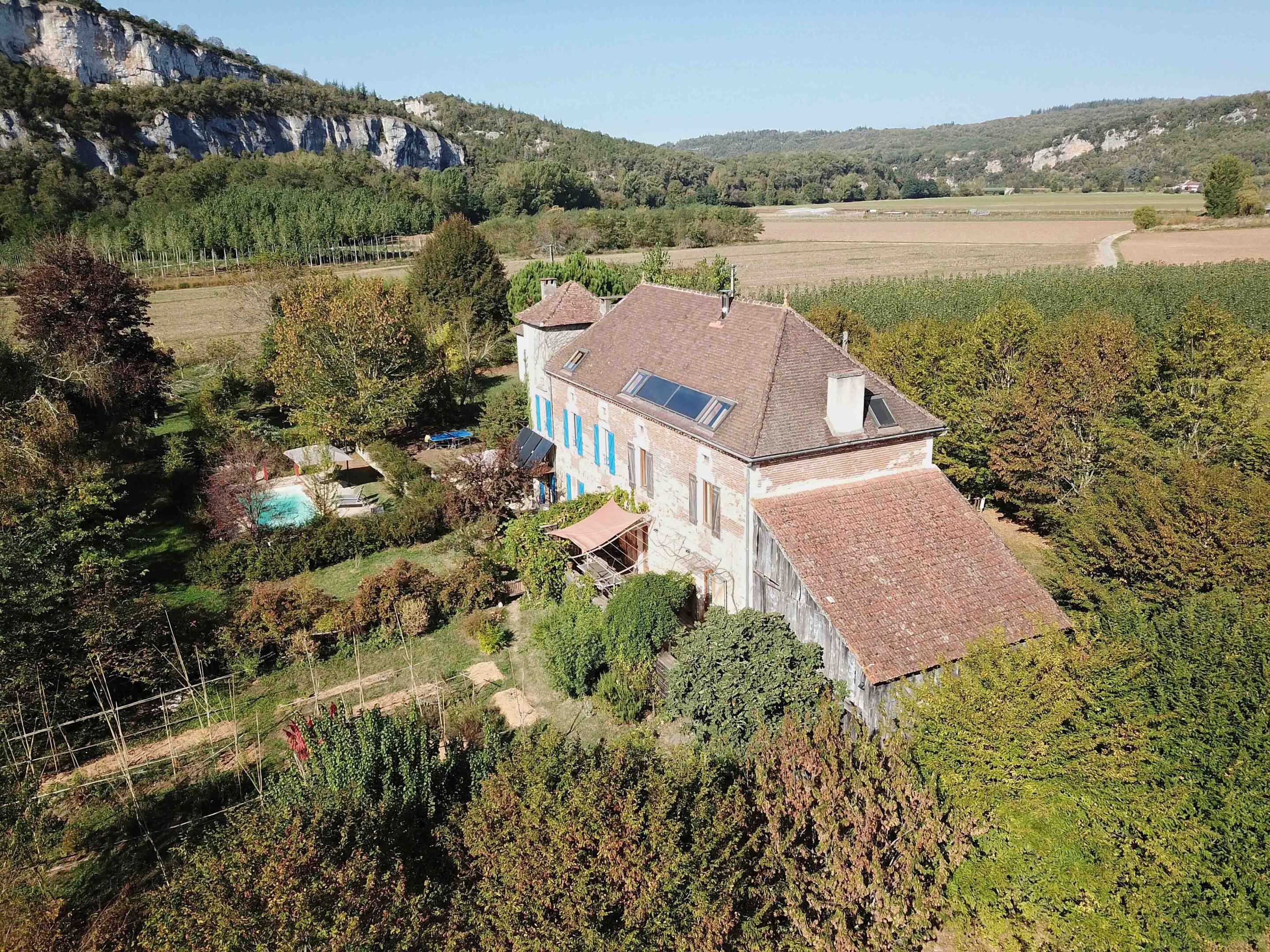 Ein geräumiges Haus mit Schrägdach, umgeben von einem Garten und einem Schwimmbad.