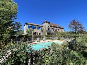 A two-story stone building with a swimming pool and outdoor seating.