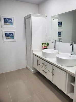 Un baño moderno con dos lavamanos, un armario y un espejo.