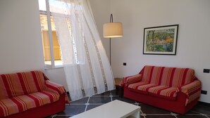 Een woonkamer met twee gestreepte banken, een witte salontafel en een vloerlamp.