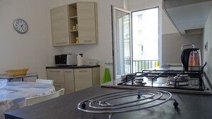 Een moderne keuken met een gasfornuis, een magnetron en een broodrooster. Er is een raam met uitzicht op gebouwen.