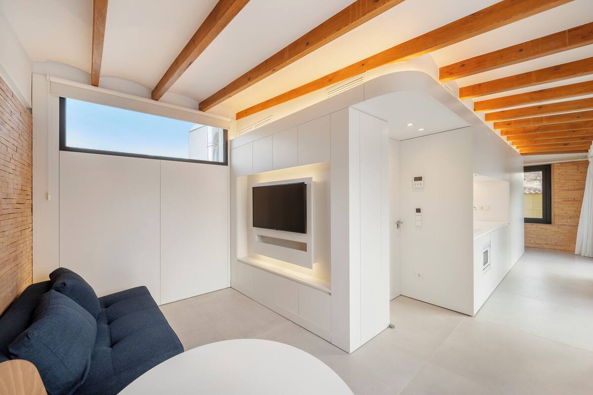 Een moderne woonkamer met een flatscreen televisie, inbouwplanken en een houten plafond.