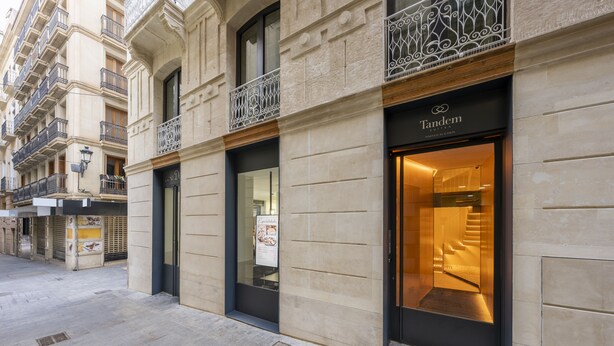 A hotel entrance with a modern design, featuring a glass facade and a staircase leading inside.
