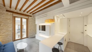 A modern kitchen with a white countertop, bar stools, and a built-in oven.