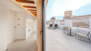 A modern interior with a balcony overlooking a historic tower and cityscape.