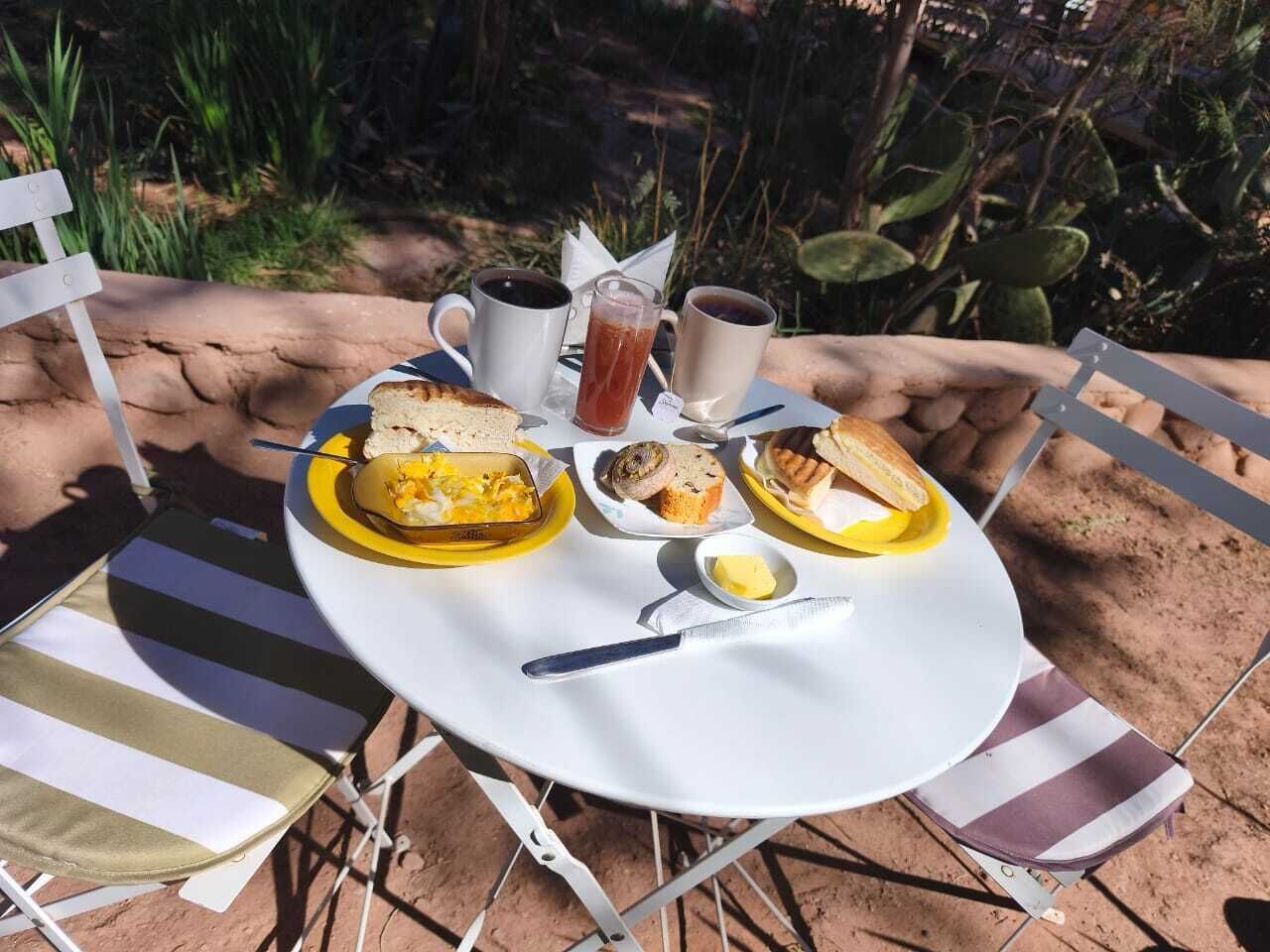 A round table with a white tablecloth, a plate of scrambled eggs, toast, and a glass of iced tea.