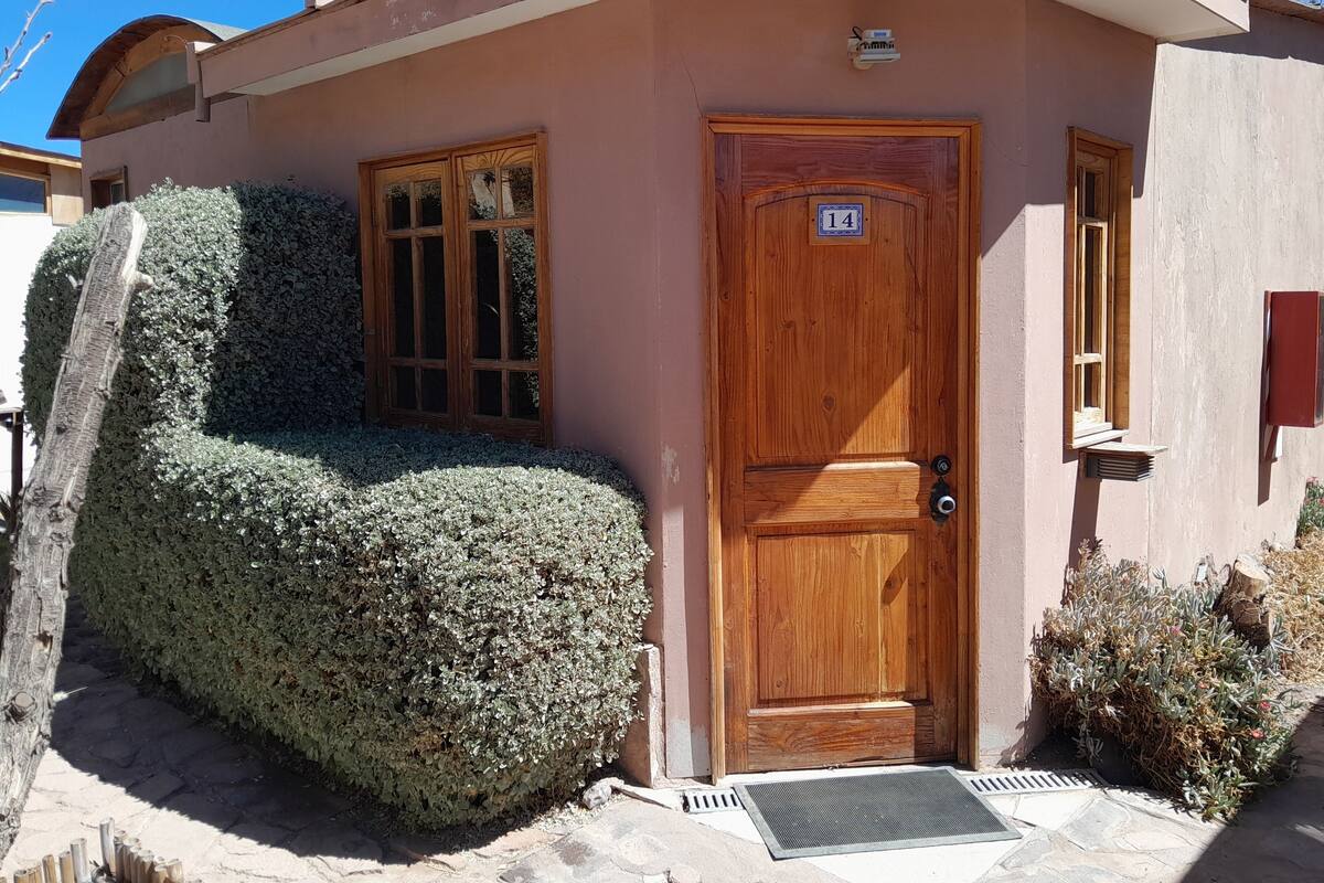 Un edificio con puerta de madera numerada con el 14, una ventana pequeña y un buzón.