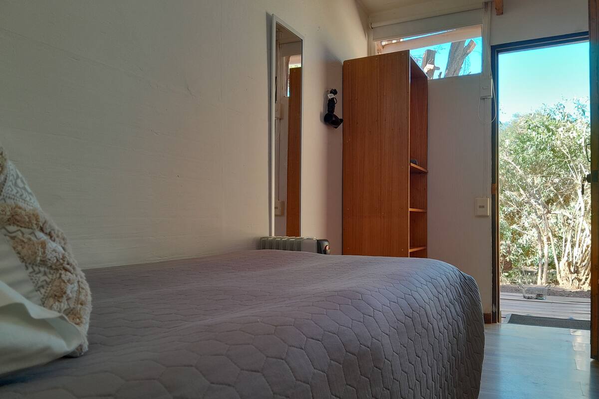Un dormitorio con una cama, un armario de madera y vistas al exterior.