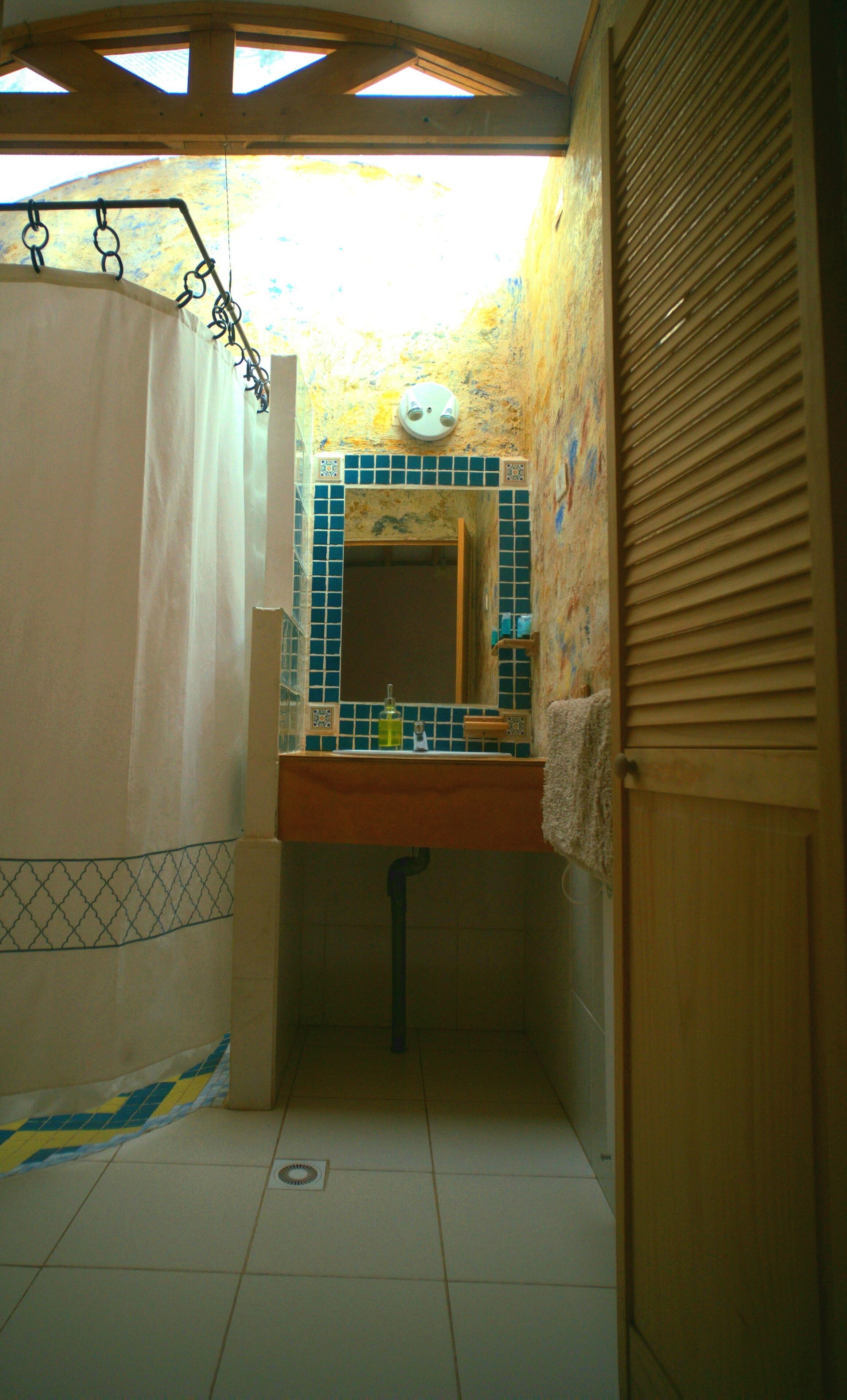 Een badkamer met een douche, wastafel en spiegel.