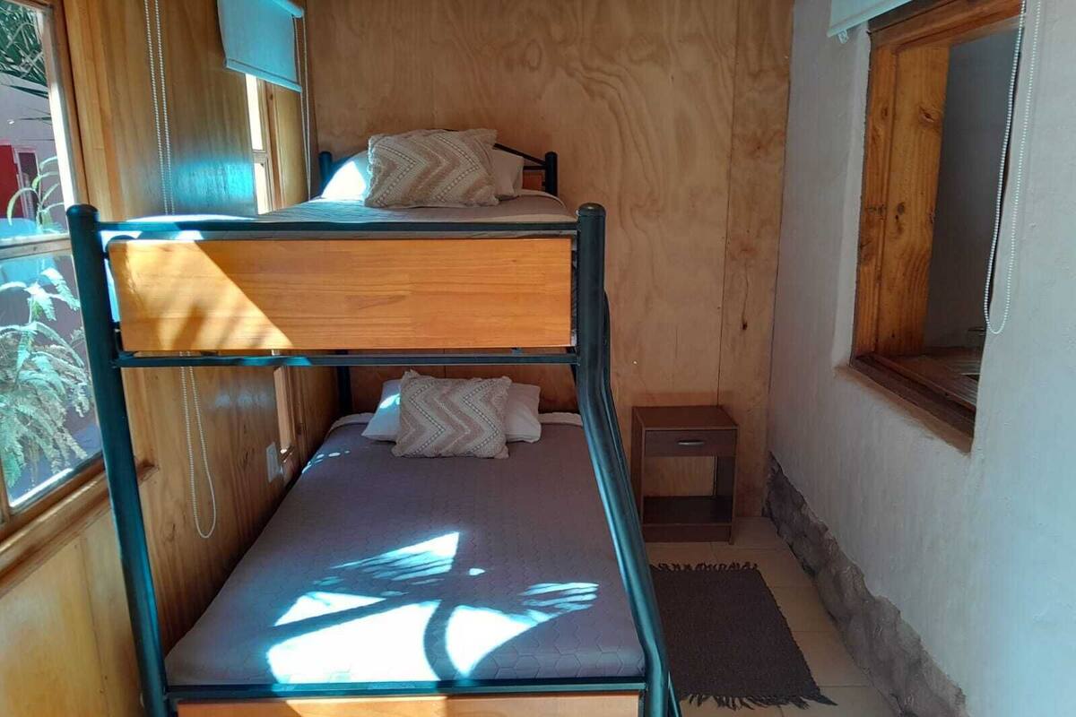Una habitación pequeña con literas y una mesita de noche.