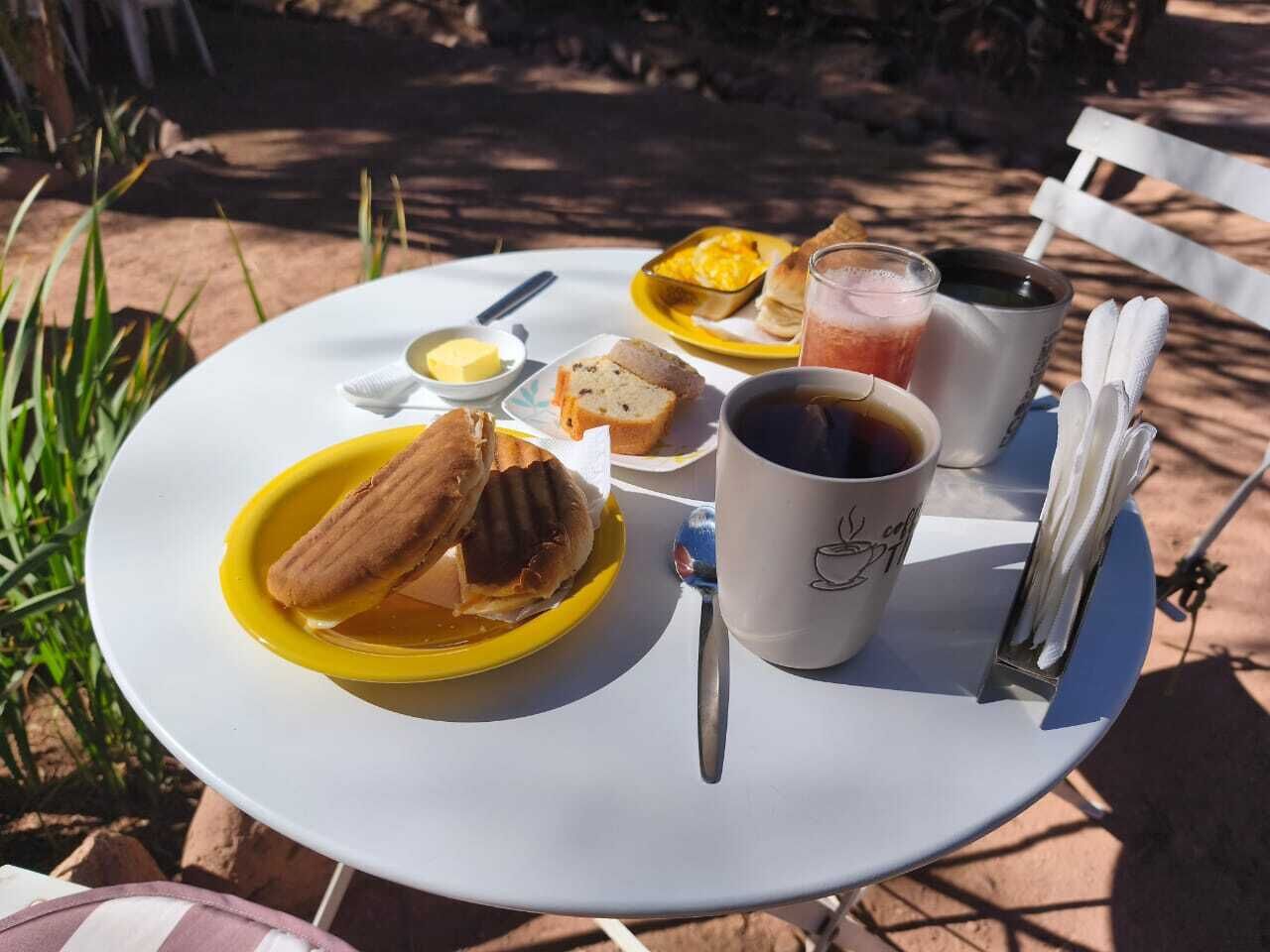 A round table with a yellow plate of food, a white mug, and a glass of iced tea.
