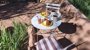 A dining table with a chair, a plate with food, a cup, and a glass.