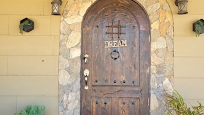 A wooden door with a stone archway, a doormat, and potted plants. - Classic and  comfort cabin within trees,vine and olive trees (Ensenada)