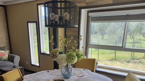 A round wooden dining table with a vase of flowers in the center, surrounded by four chairs. - Classic and  comfort cabin within trees,vine and olive trees (Ensenada)