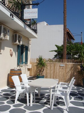 A patio with a table and four chairs, a potted plant, and a barrel. - Pansion Konstantinos (Skiathos)