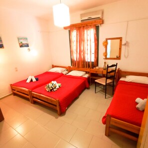 A hotel room with two single beds, a wooden desk, a chair, and a small table. - Pansion Konstantinos (Skiathos)