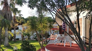 A resort with a red and white staircase leading to a covered seating area with white plastic chairs. - Luxury-Unique-Homes 1 Capo Vaticano Tropea (Santa Maria Di Ricadi)