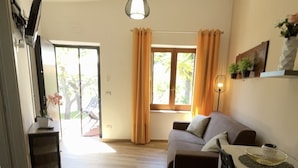 A modern living room with a sofa, a dining table, and a kitchen area. - Luxury-Unique-Homes 1 Capo Vaticano Tropea (Santa Maria Di Ricadi)