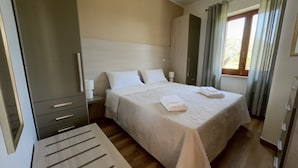 A neatly arranged bedroom with a bed, bedside tables, and a wardrobe. - Luxury-Unique-Homes 1 Capo Vaticano Tropea (Santa Maria Di Ricadi)