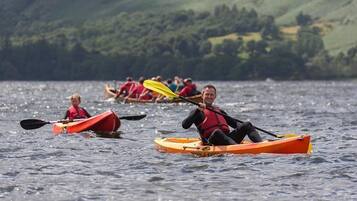 Un groupe de personnes pratiquant le kayak sur un lac, avec une chaîne de montagnes en arrière-plan.