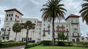 Un edificio grande e bianco con numerosi balconi e una palma al centro.