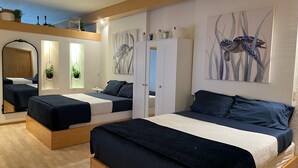 Una camera d'albergo con due letti, un armadio e opere d'arte alle pareti.