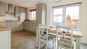 A modern kitchen with a dining area, featuring a large window, wooden cabinets, and a table set for dining. - 10 Goodhope Gardens (Aberdeen)