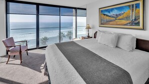 Una camera da letto con un letto grande, una sedia, un quadro e vista sull'oceano.