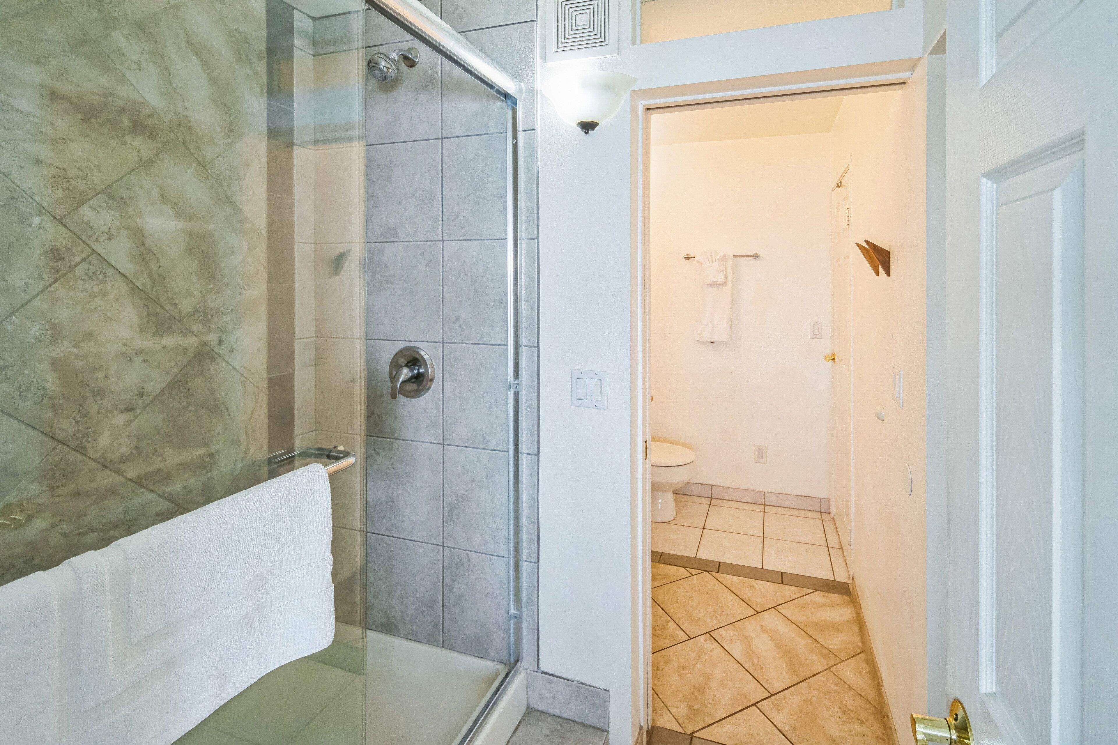 A bathroom with a glass shower enclosure, a white bathtub, and a toilet.
