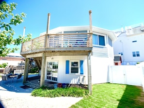 Een huis met twee verdiepingen, een balkon, een overdekte patio en een kleine tuin.