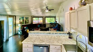 A spacious living area with a kitchen, dining area, and a ceiling fan. - ❤️Amazing Round House - Easy Self Check-In, Just Steps to Beach! (Carolina Beach)