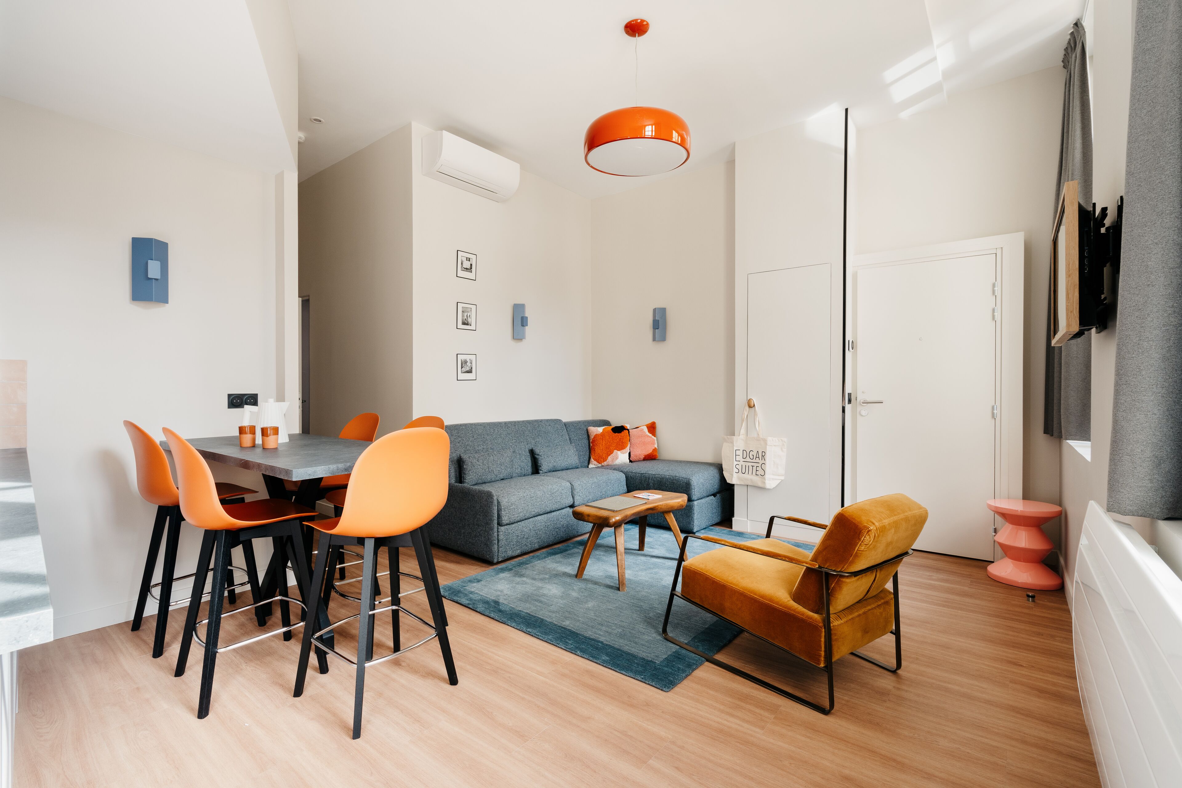 Una sala de estar moderna con un sofá, sillas, una mesa de centro y un comedor con una mesa y sillas.