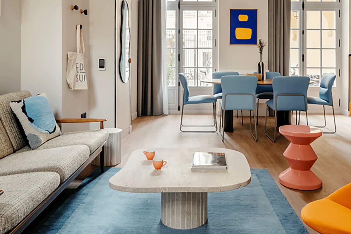 A modern living room with a sofa, a coffee table, and a vibrant orange chair.